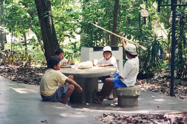 Crianças indígenas conversando à mesa de uma praça