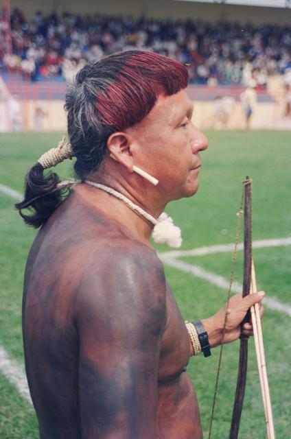 Índio com arco e flecha diante de um campo de futebol