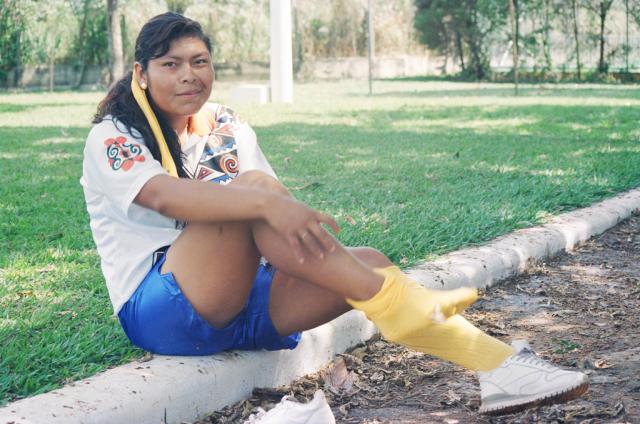 Mulher indígena sentada com uniforme de futebol