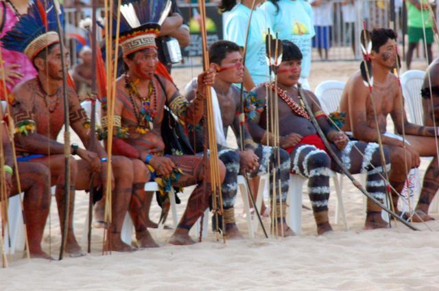 Vários índios sentados com arcos e flechas