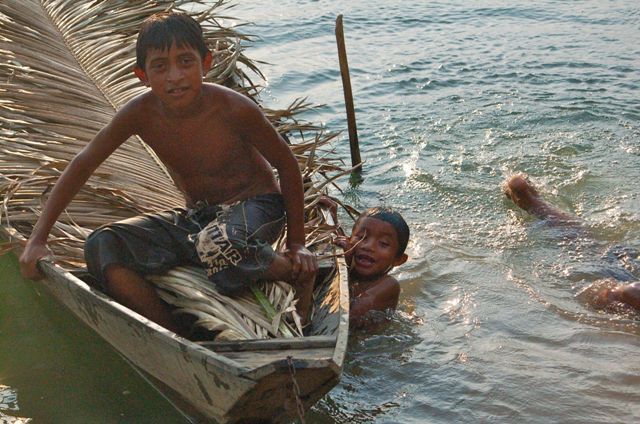 Meninos índios em canoa e rio