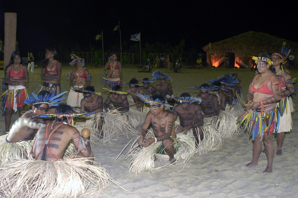 índios com aderços e roupas típicas sentados na arena