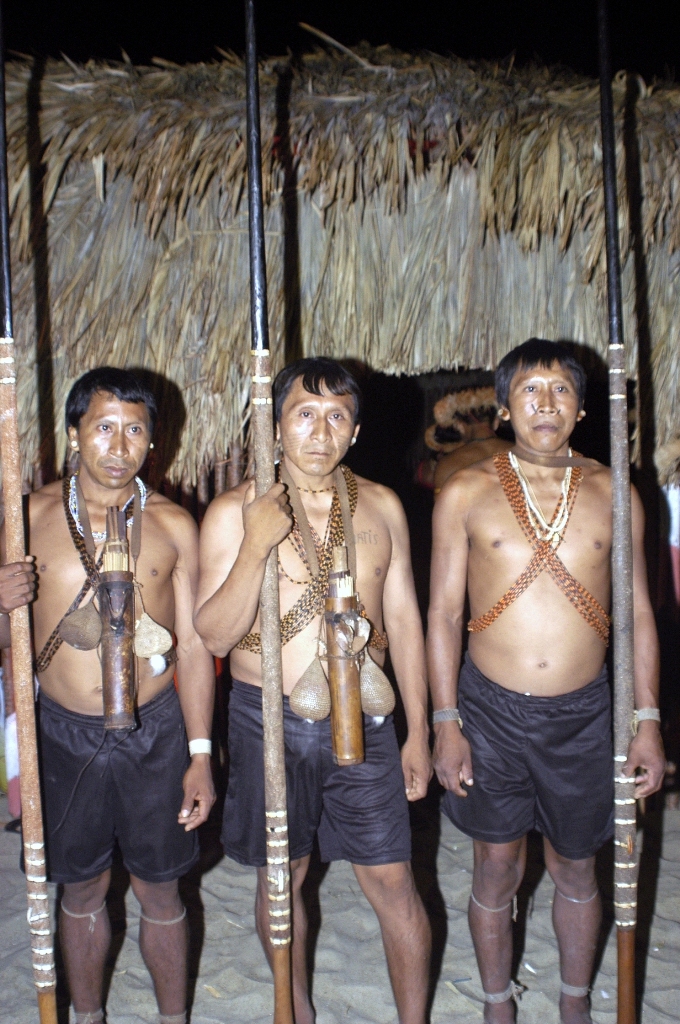 três índios posando para foto com lanças